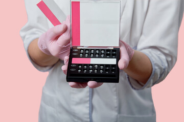 Dentist doctor shows close-up of a box with braces. Hands in medical gloves.