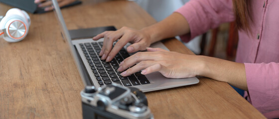 Female female university student typing on laptop while sitting at worktable with her friend in library