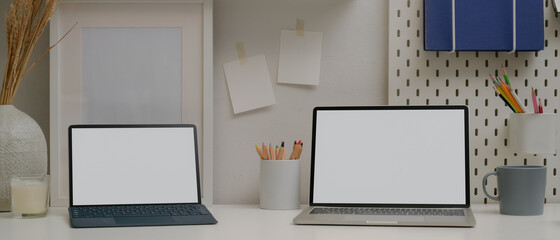 Comfortable workspace with mock up laptop, tablet with keyboard, stationery and decorations