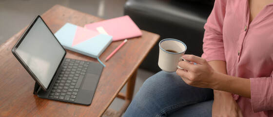 College student take break with coffee while online studying with mock-up tablet in living room