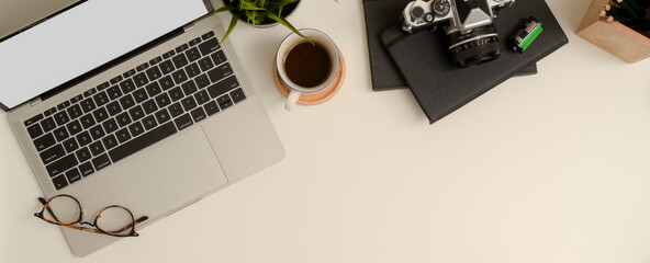 Minimal worktable with copy space, mock-up laptop, glasses, coffee cup, camera, stationery and decoration