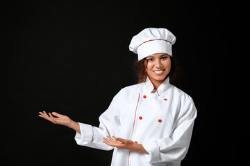 Female African-American chef showing something on dark background