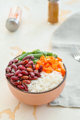 Bowl with tasty rice, beans and vegetables on table