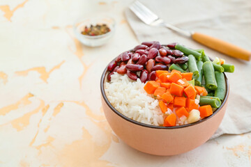 Bowl with tasty rice, beans and vegetables on table