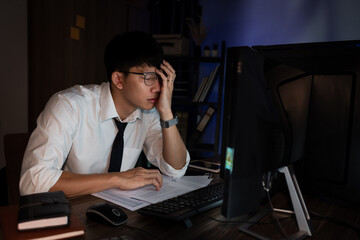 Asian businessman concentrated working until late overtime in office at night

