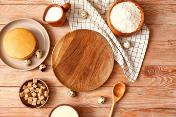 Tasty pancakes with ingredients and plate on wooden background