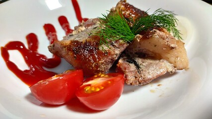 kebabs on a white plate, decorated with a sprig of dill, sliced tomato, sliced onion rings and thin strips of ketchup.