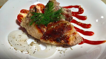kebabs on a white plate, decorated with a sprig of dill, sliced tomato, sliced onion rings and thin strips of ketchup.