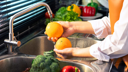 Woman hands washing Vegetables for Preparation of vegan salad on the worktop near to sink in a modern kitchen, Homemade healthy food concept.