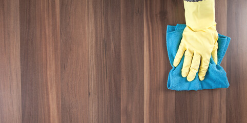 Hand cleaning wooden table at home.