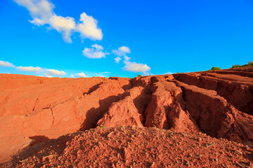 The red land is under the blue sky and white clouds.