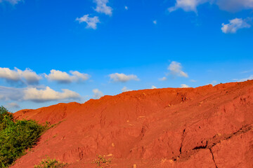 The red land is under the blue sky and white clouds.