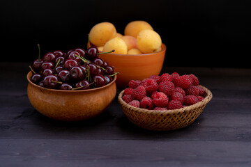 Cherry, raspberries and apricots on a wooden background