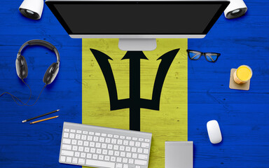 Barbados flag background with headphone,computer keyboard and mouse on national office desk table.Top view with copy space.Flat Lay.