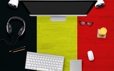 Belgium flag background with headphone,computer keyboard and mouse on national office desk table.Top view with copy space.Flat Lay.