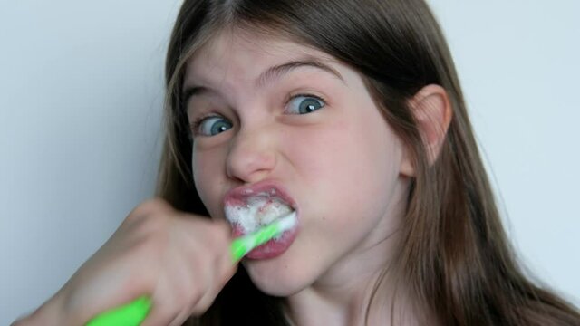 little girl brushes her teeth, indulges, grimaces
