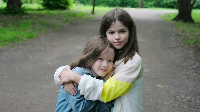 little smiling girls, sisters, best friends hug in the park, children hug each other