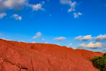 The red land is under the blue sky and white clouds.