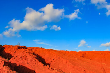 The red land is under the blue sky and white clouds.