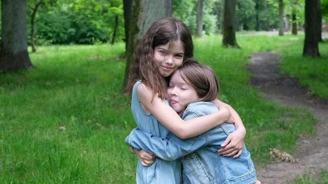 little children, girls, sisters, best friends laugh, hug each other in the forest, have fun, laugh