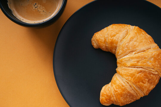 Top view close up - Golden crossiant with hot coffee over orange background.