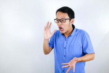 Close up portrait of a young asian man shouting loud and angry facce with arm at his face isolated over white