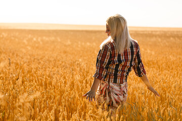 Woman in a wheat field on the background of the setting sun