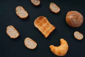 Top view - Group of many type of bread over black background.
