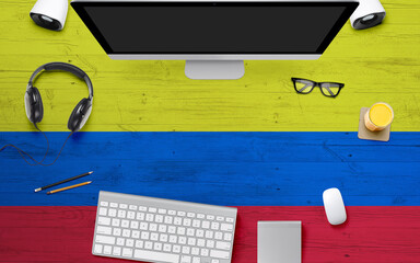 Colombia flag background with headphone,computer keyboard and mouse on national office desk table.Top view with copy space.Flat Lay.
