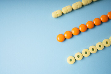 Yellow and orange medicine pills in line shape over blue background.