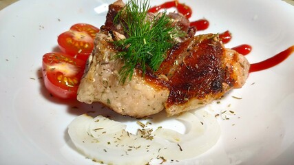 kebabs on a white plate, decorated with a sprig of dill, sliced tomato, sliced onion rings and thin strips of ketchup.