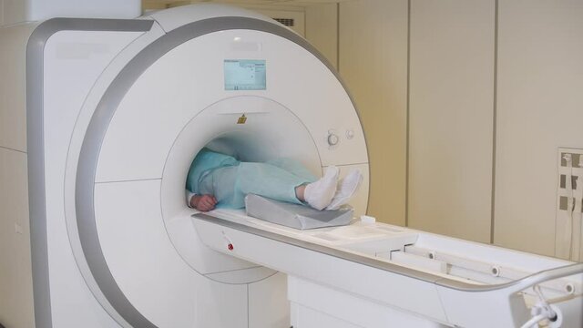 Magnetic resonance imaging, asian woman doctor performs a magnetic tomographic examination of a adult man, MRI, modern technologies in medicine, end of the procedure.