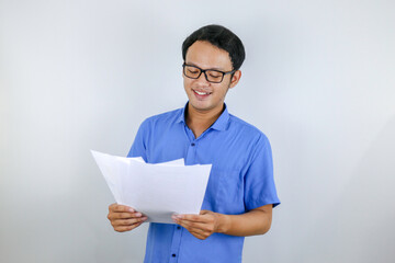 Young Asian Man is smile and happy when looking on paper document. Indonesian man wearing blue shirt.