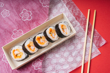 Fresh and delicious maki and nigiri sushi roll in a box set on japanese style paper background.