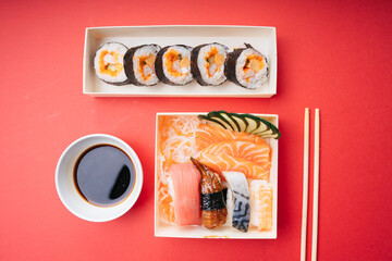 Top view - Japanese sushi and sashimi box set over red background.