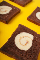 Dark chocolate roll sliced bread over yellow background.