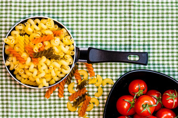Small mini frying pan with tricolor raw fusilli pasta in a rustic composition.
