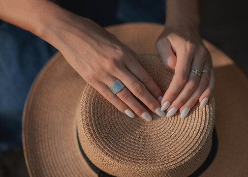 Hands With Gray Nails On A Straw Hat Close-up