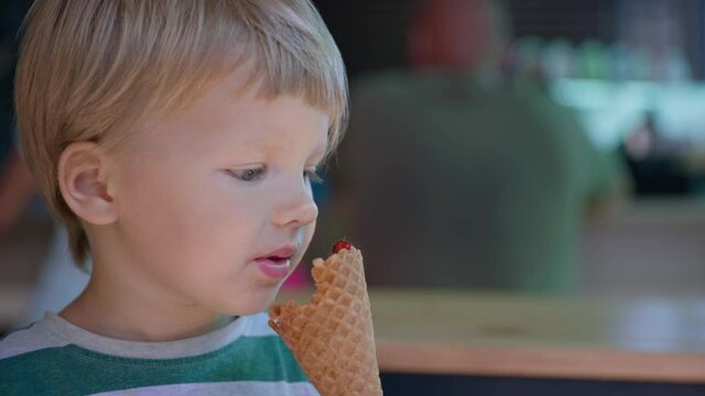 ice cream, little attractive boy enjoys licking his tongue in the summer cool dessert popsicles in waffle cup during summer vacation