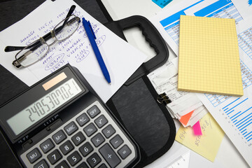 business office desk closeup - financial reports, analysis and accounting, set of documents, tables and graphs, various items for bookkeeping, calculator