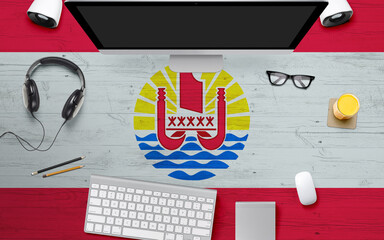 French Polynesia flag background with headphone,computer keyboard and mouse on national office desk table.Top view with copy space.Flat Lay.