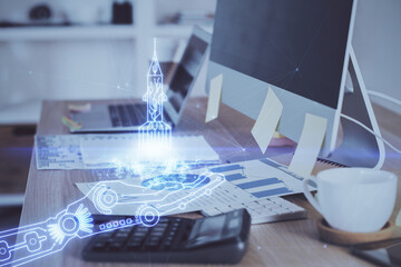 Desktop computer background in office and start up theme hologram drawing. Double exposure. Startup concept.