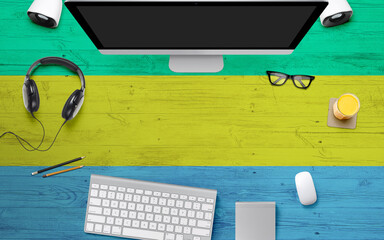 Gabon flag background with headphone,computer keyboard and mouse on national office desk table.Top...