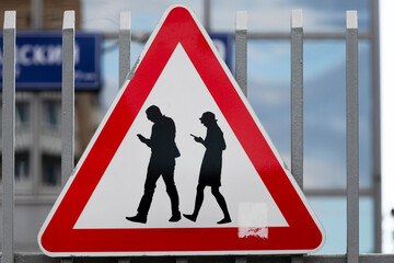 Road sign "Attention people with smartphones" installed near an entrance in an office of the Internet company 