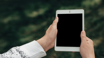 Close up wide angle mock up shot of young manager or ceo hands holding white tablet pc with black touchscreen. Male wear casual clothes and make a broadcast for his friend through video calling. 
