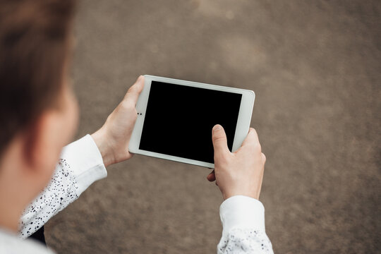 Close up shot of hands hold white tablet pc. Young hipster man have a rest after a long interview with the IT company. Mock up image of digital gadget deskstop with copy space. Distance education.