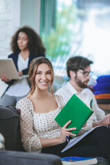 Girl with bright hair holding a book, friends nearby