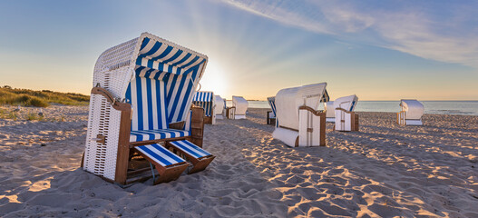 Sunset at calm beach with beach chairs 