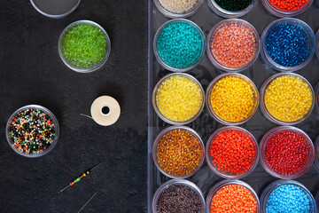 Beads with thread and needle for needlework .Beads in a box of different colors. Top view