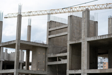 Reinforced concrete construction site and crane in cloudy weather.